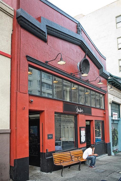 a man sitting on a bench outside of a red building