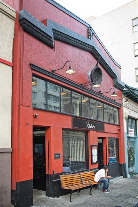 a man sitting on a bench outside of a red building