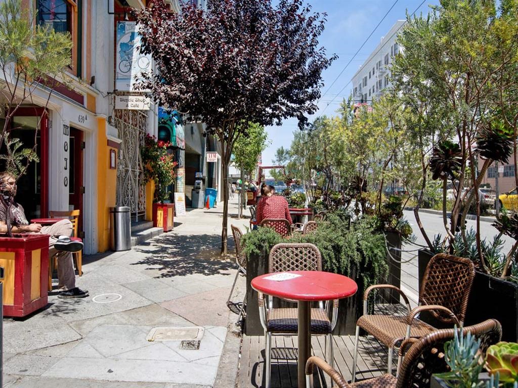 a city street with tables and chairs and trees