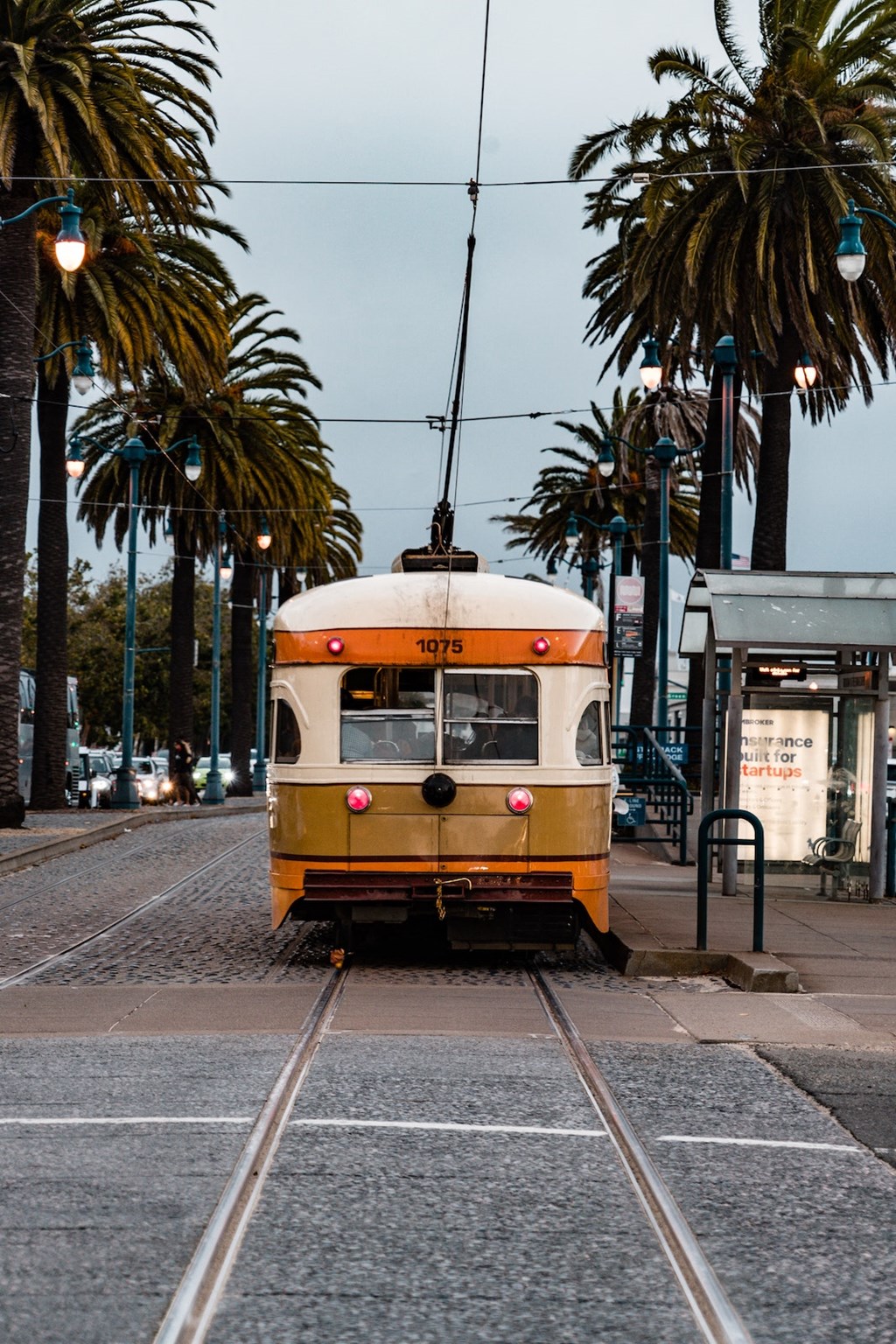 a yellow streetcar on the tracks on a city street