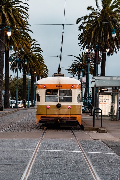 a yellow streetcar on the tracks on a city street