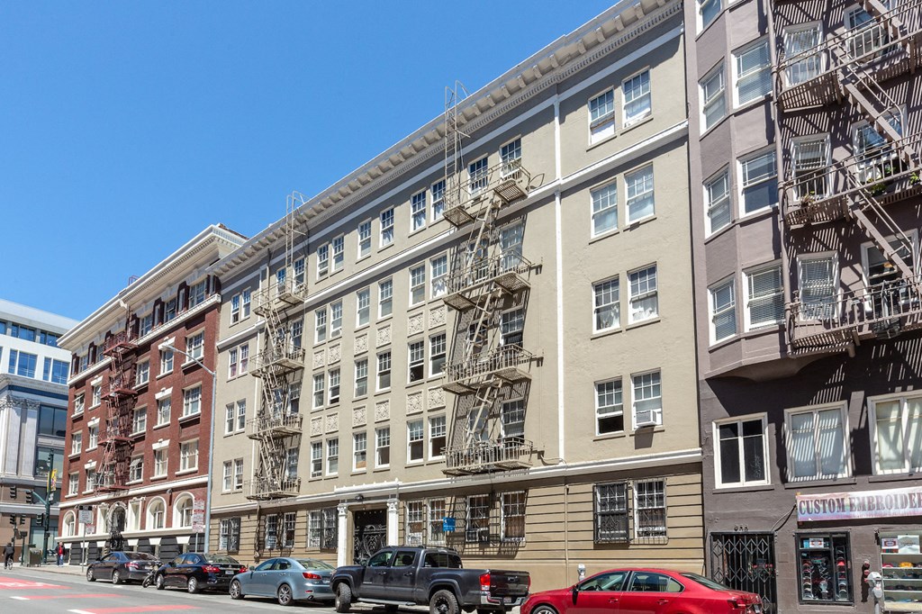 a large apartment building on a city street with cars parked in front