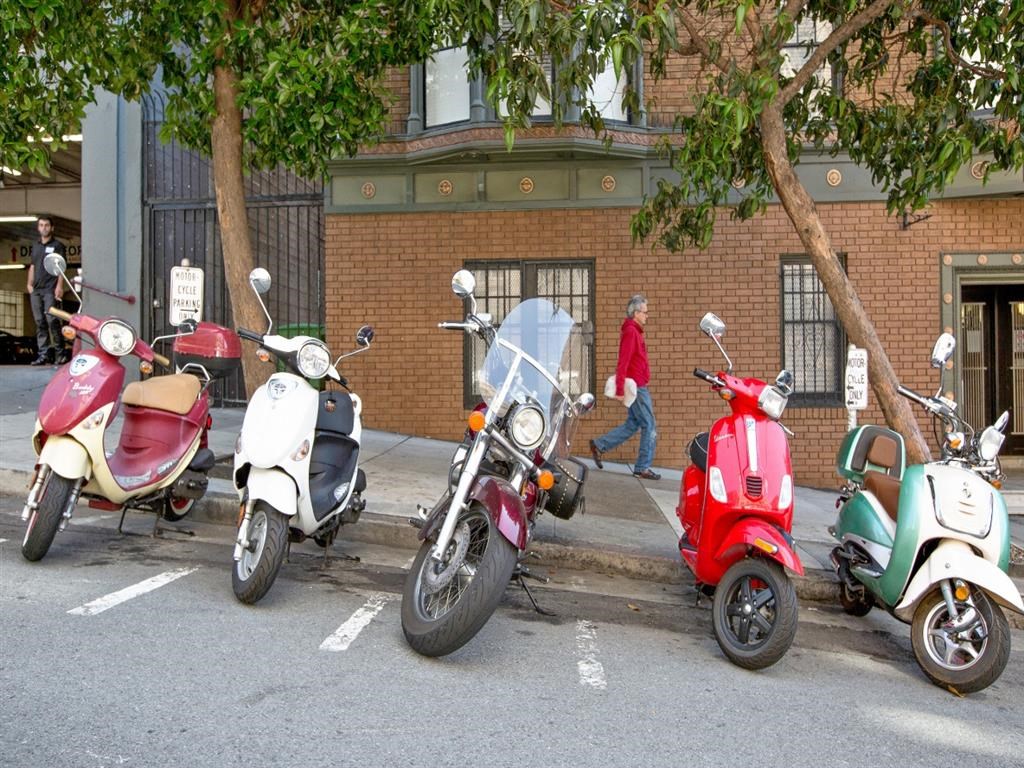 a row of scooters parked on the side of a street