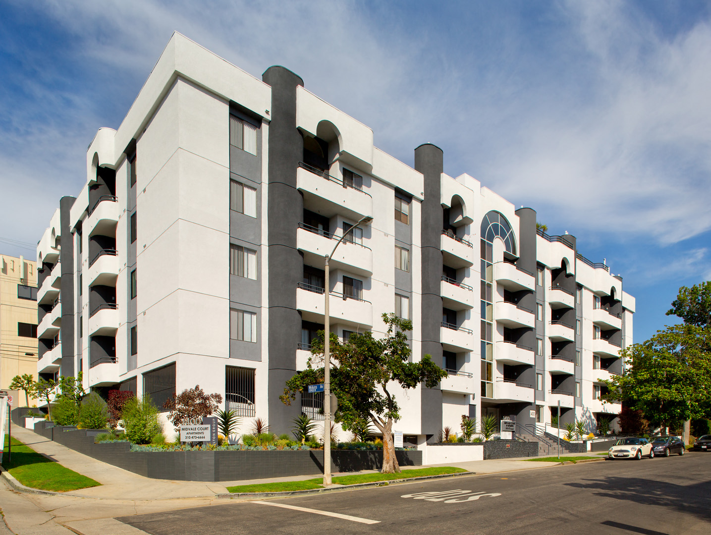 a large white apartment building with a street in front of it