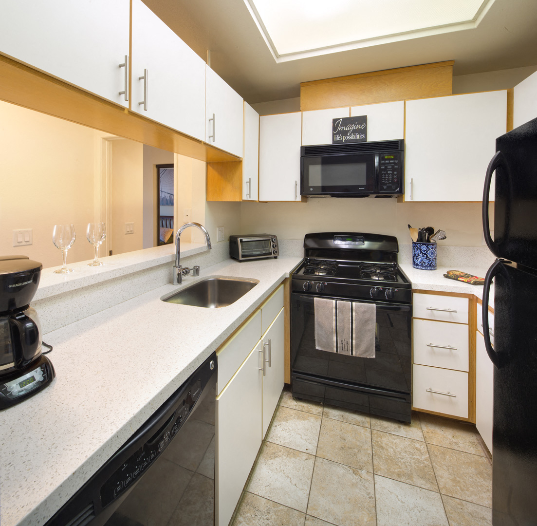 a kitchen with white cabinets and a sink and a stove