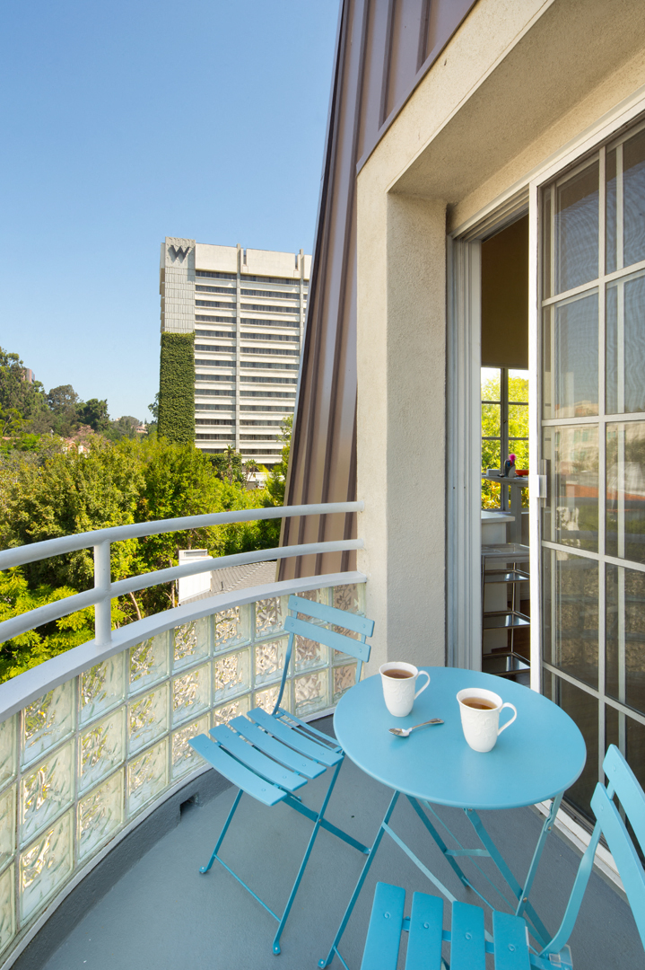 a balcony with a blue table and chairs and a cup of coffee