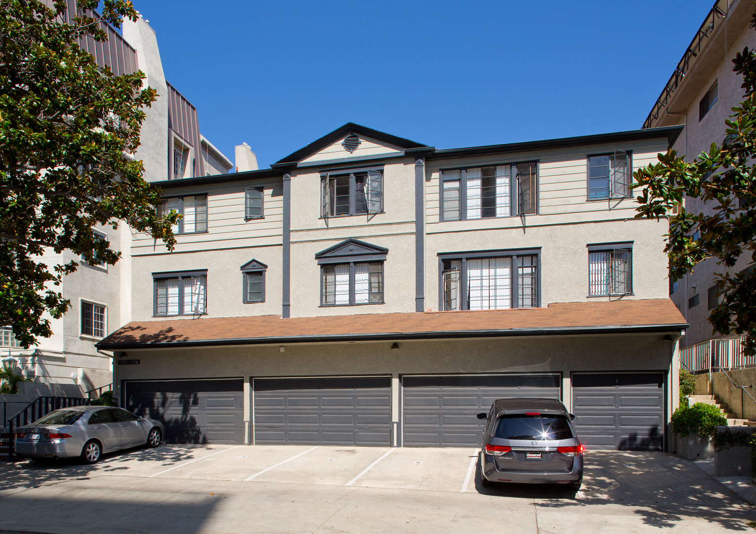 a three story apartment building with two cars parked in front of it