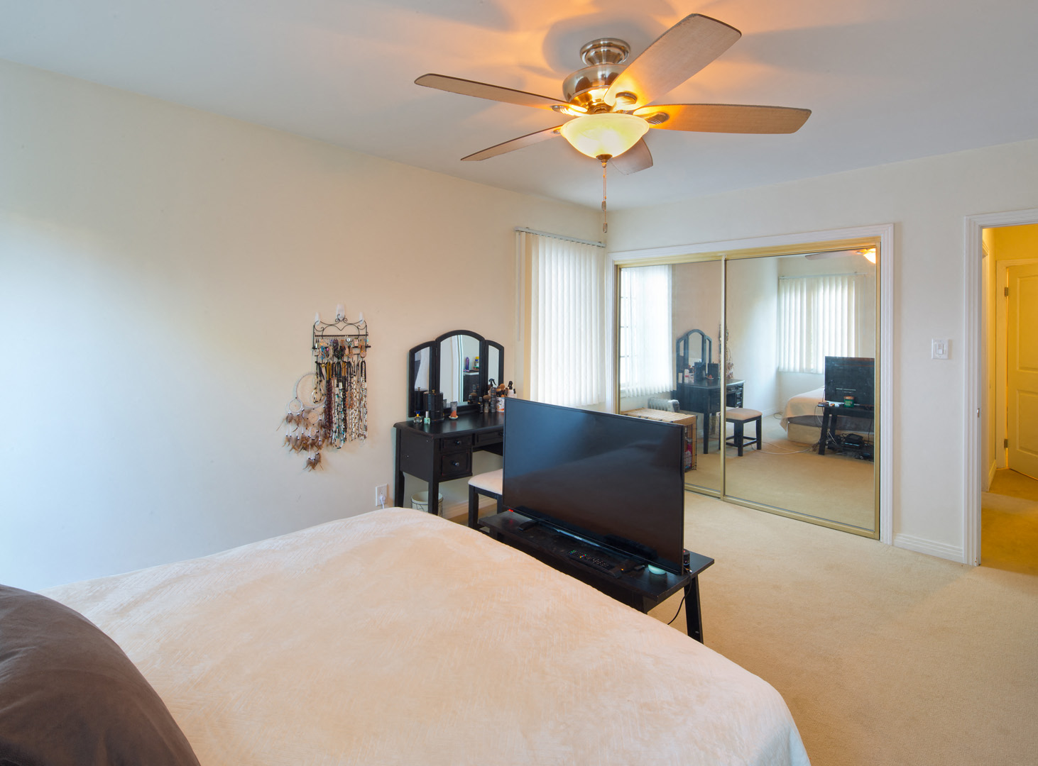 a bedroom with a bed and a ceiling fan and a mirror