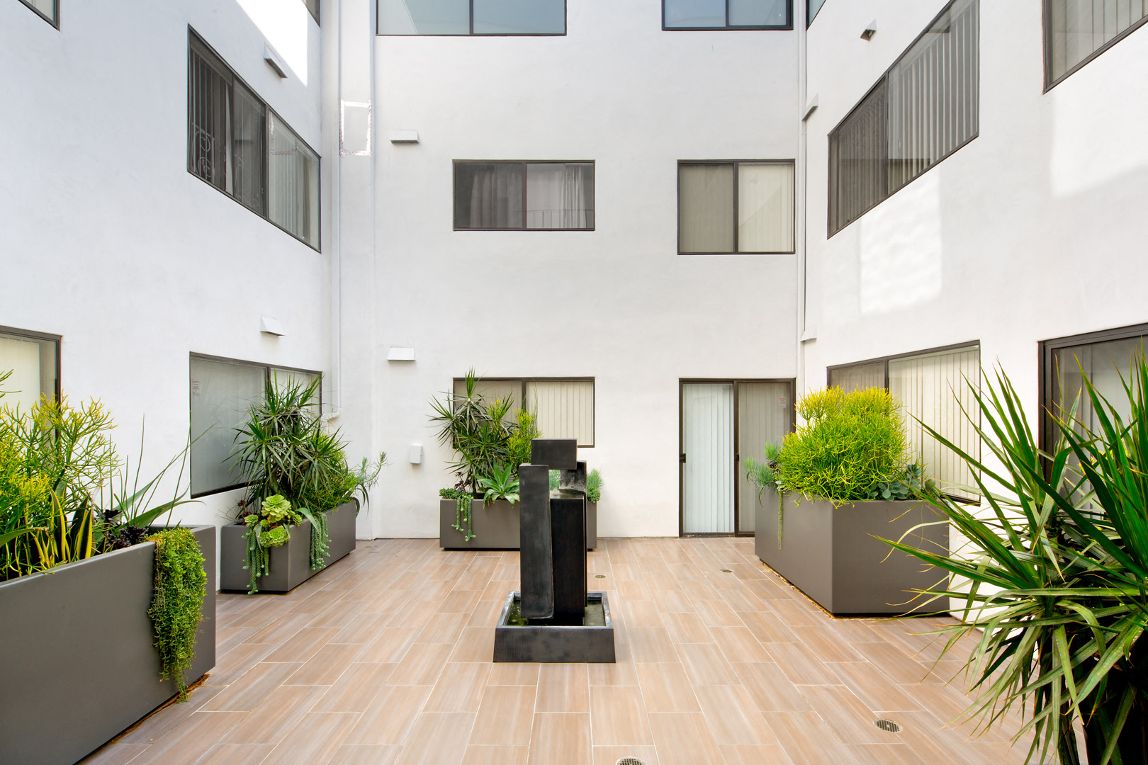 arium of an apartment building with a wood floor and large pots of plants