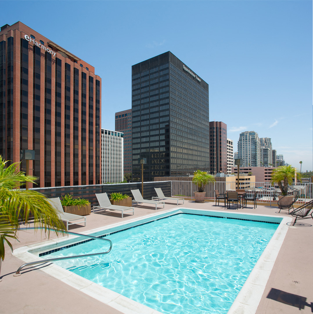 a pool on the rooftop of a building with a city in the background
