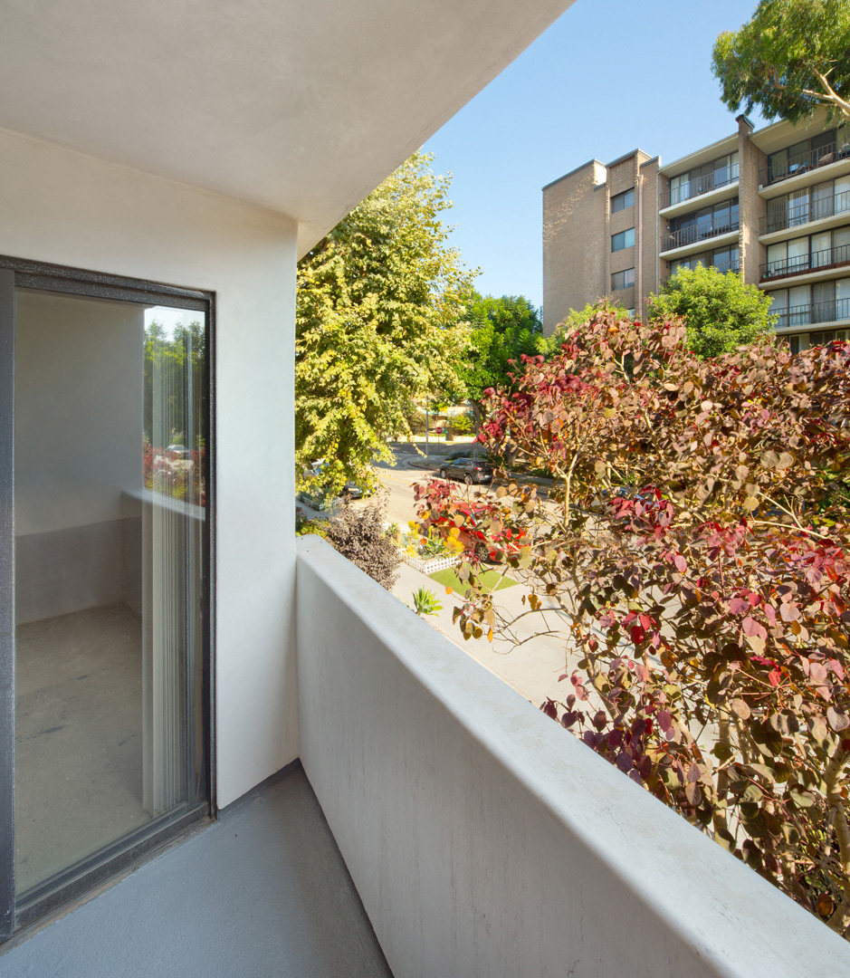 a balcony with a door and a tree and some buildings
