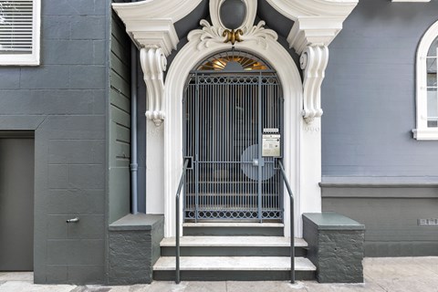 A grey building with a white door and a fan on the wall.