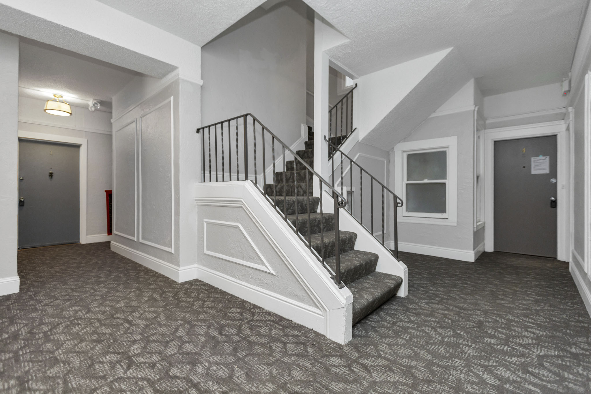 A hallway with a staircase and a patterned carpet.