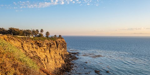 a cliff overlooking the ocean with a house on top of it