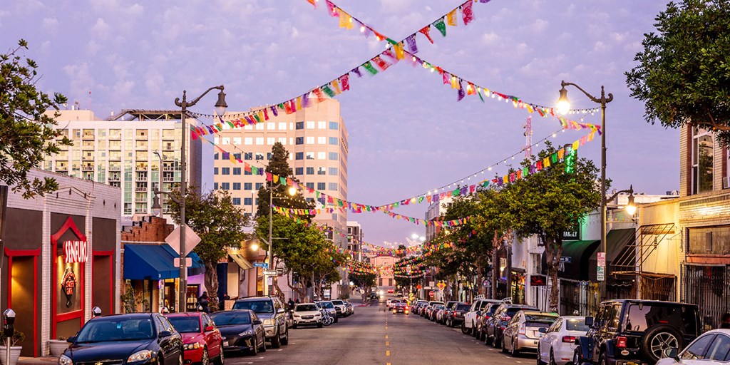 a city street with cars parked on the side of the road and strings of flags