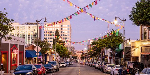 a city street with cars parked on the side of the road and strings of flags