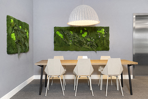 a dining room with a table and chairs and a green wall hanging on the wall