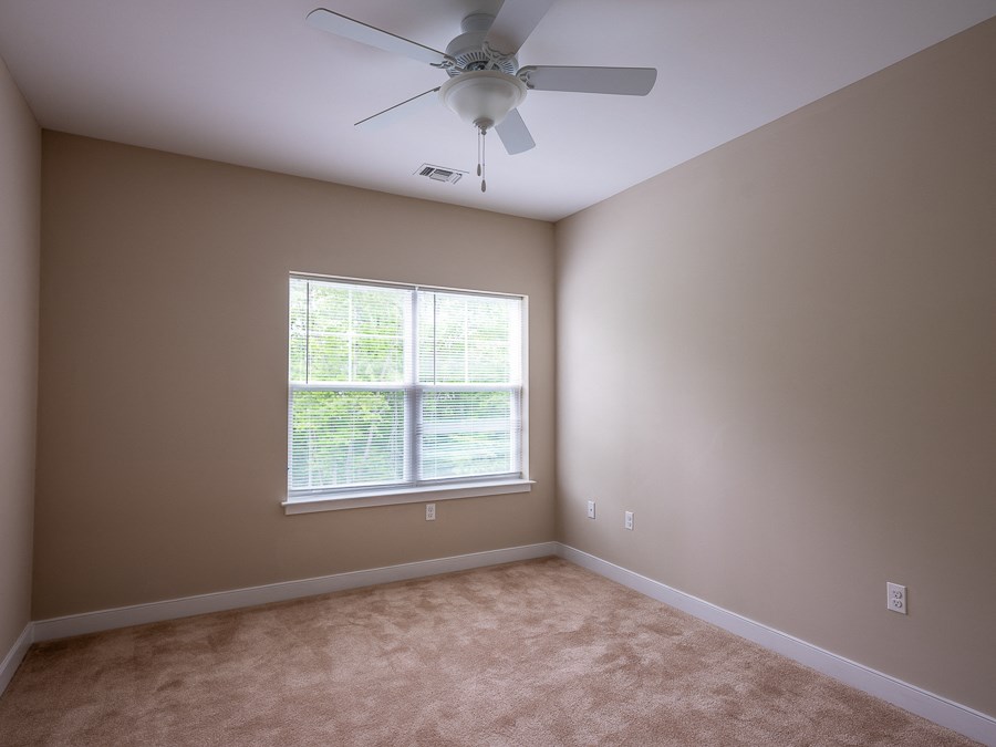 an empty room with a ceiling fan and a window
