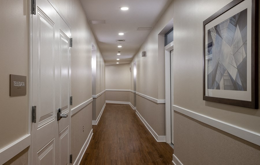 a long hallway with white walls and wood floors and a painting on the wall