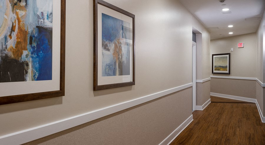 a hallway with paintings on the wall and wooden floors