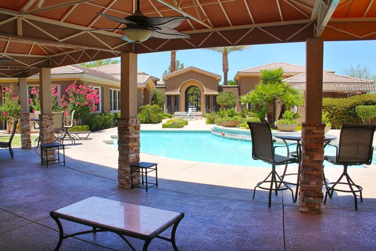 a swimming pool with patio furniture and umbrellas