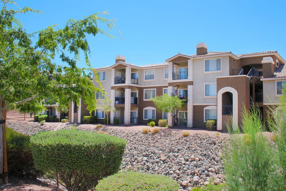 an apartment building with gravel and trees in front of it