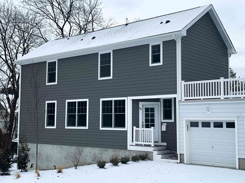 A house with a grey siding and a white garage door.