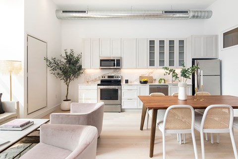 a kitchen and dining room with white cabinets and appliances and a wooden table