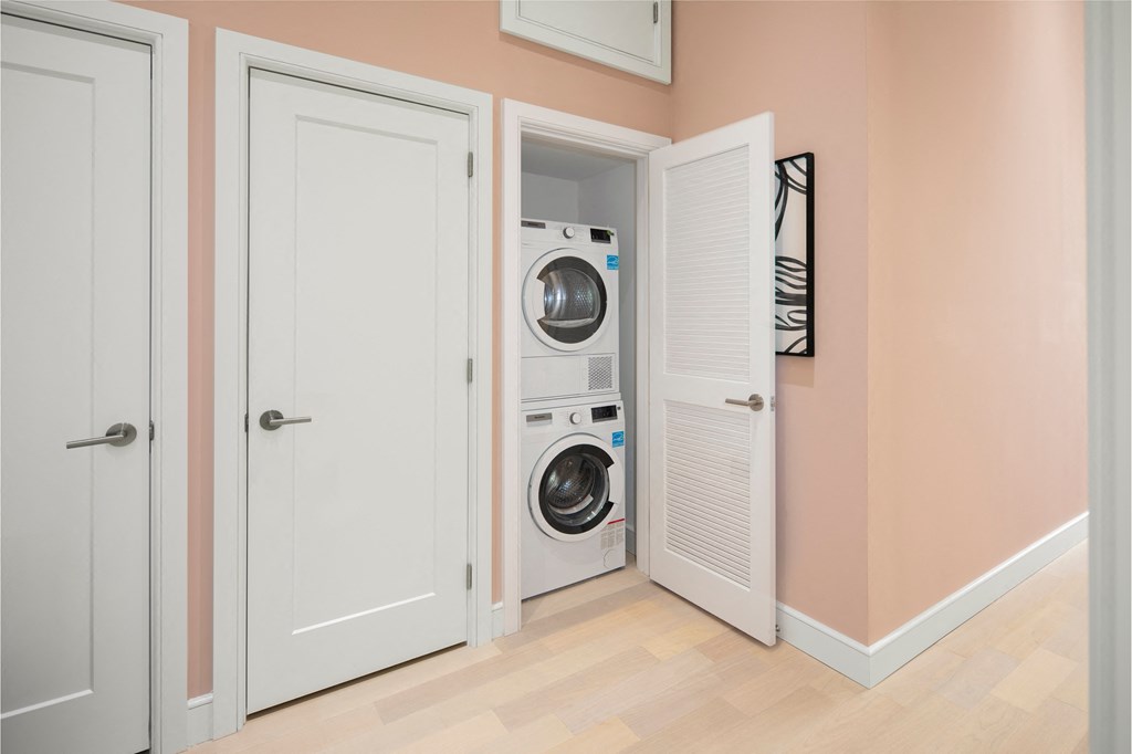 a small laundry room with a washing machine and a door to the closet