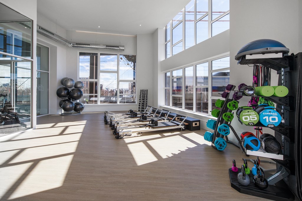 a workout room with weights and cardio equipment in a building with large windows