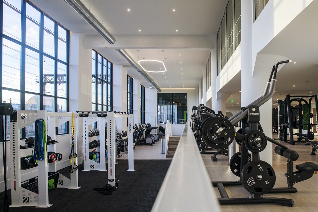 a gym with weights and other exercise equipment in a building with large windows