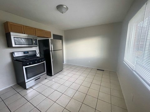 a kitchen with a tiled floor and a stainless steel refrigerator