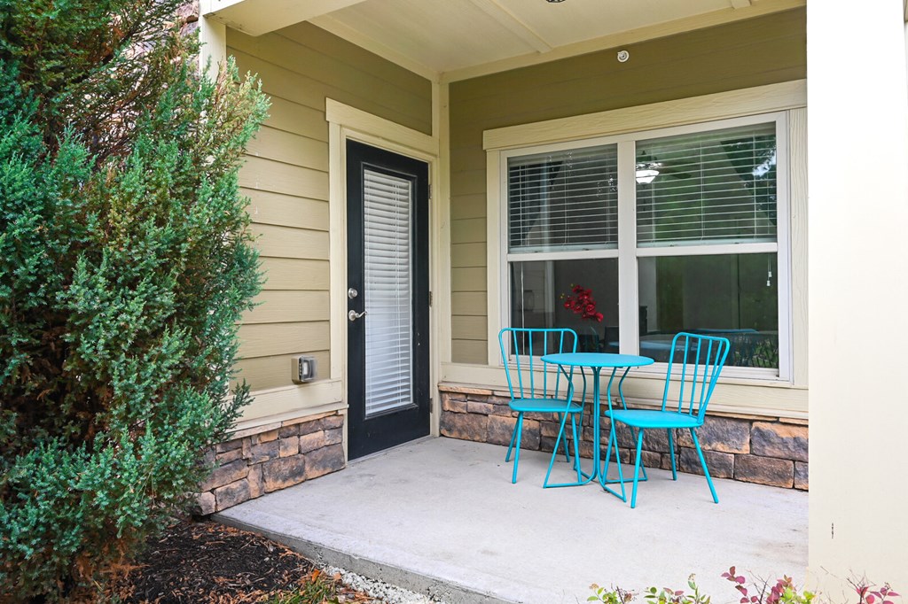 a patio with blue chairs and a table and a door