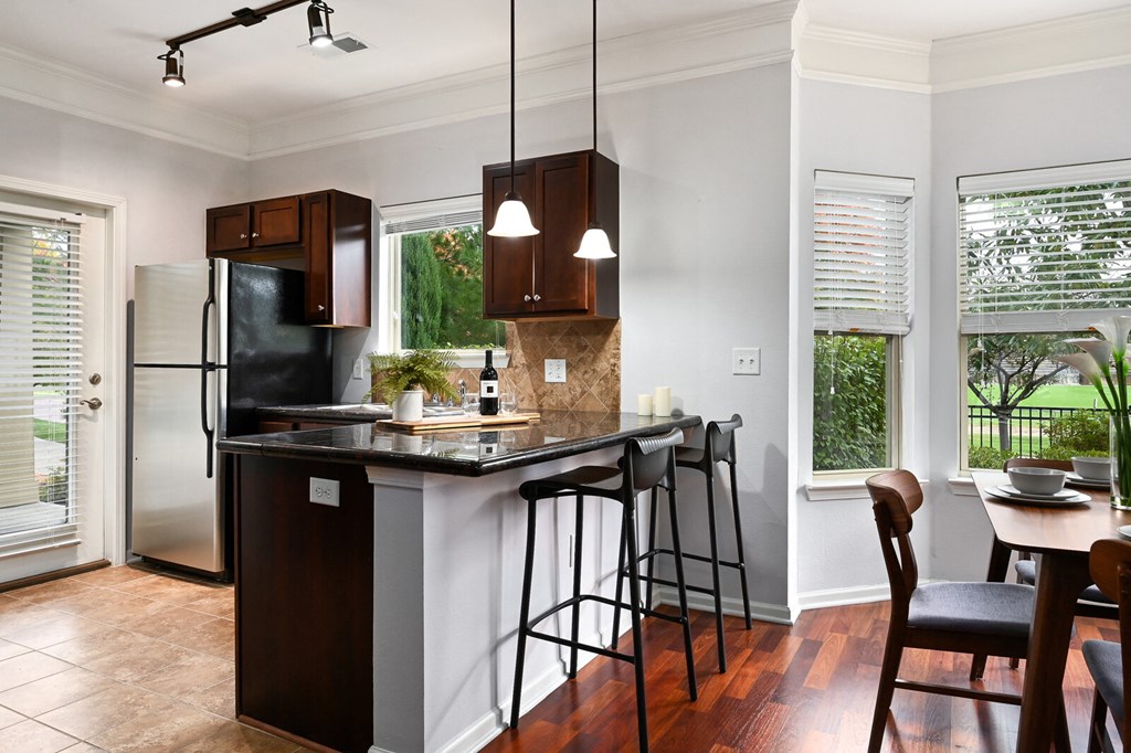 a kitchen with an island with stools and a stainless steel refrigerator