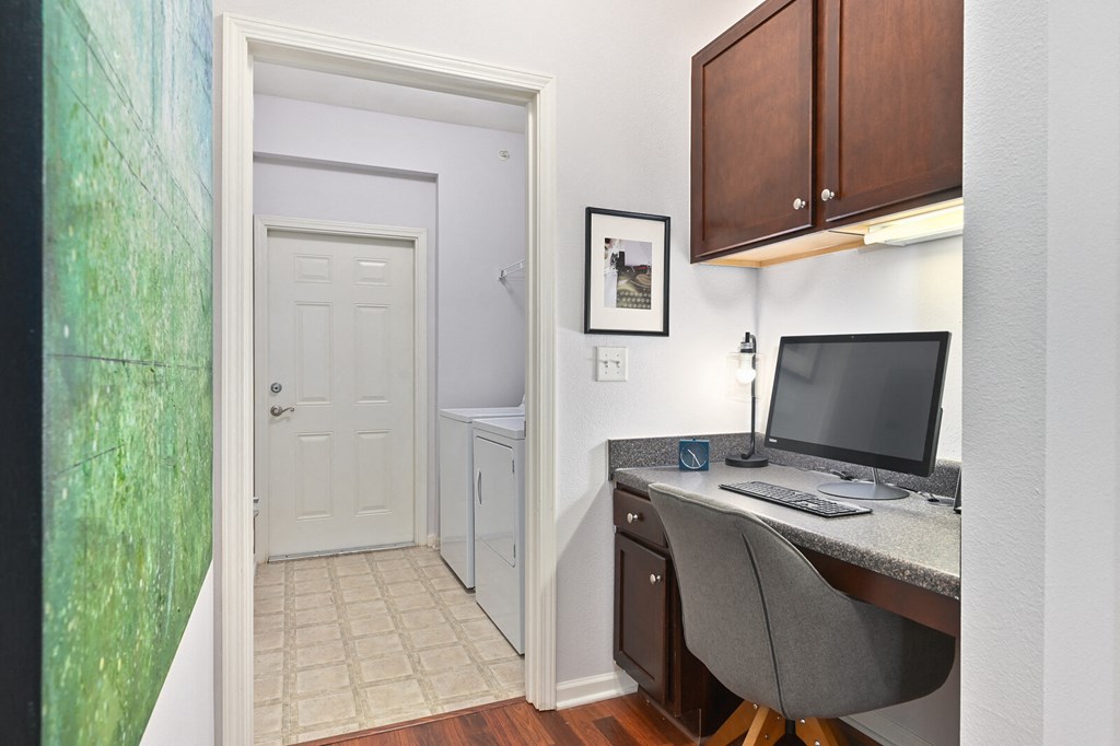 a home office with a computer desk and a door to a bathroom