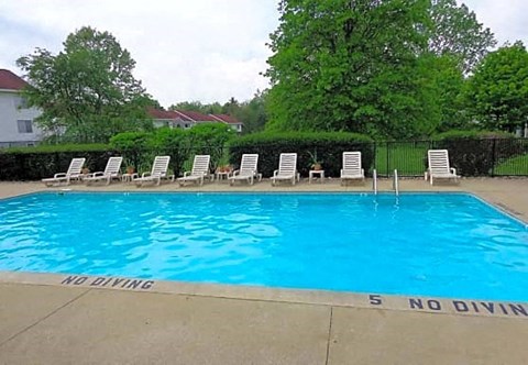 a large blue pool with white chairs