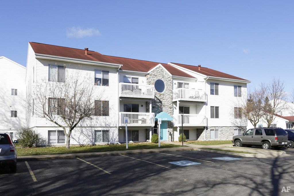 a parking lot in front of a white apartment building