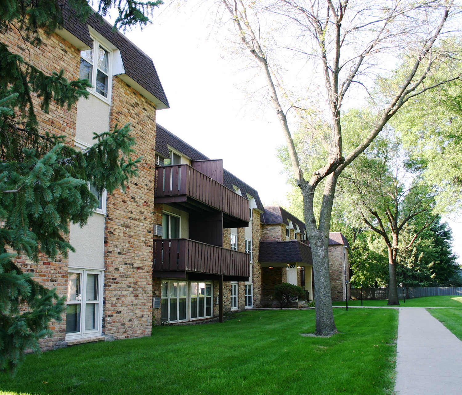 a brick apartment building with green grass and trees
