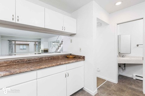 A modern kitchen with white cabinets and a wooden countertop.