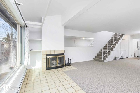 A spacious living room with a fireplace and a staircase.
