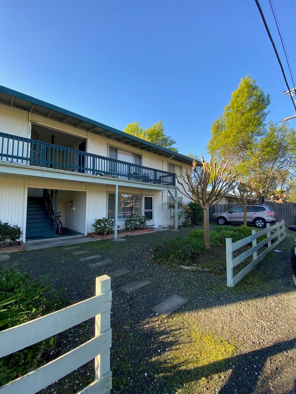 a white house with a white fence and a car parked in front of it