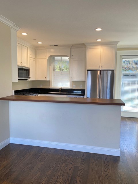 A kitchen with white cabinets and a wooden island.