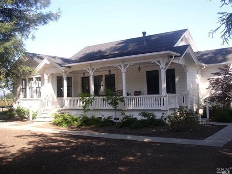 a white house with a white porch and a black roof