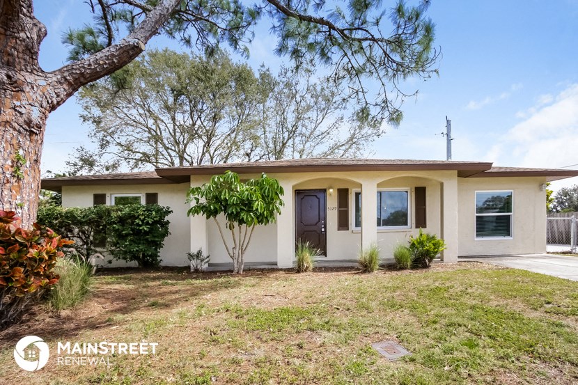 a small white house with a yard and a tree