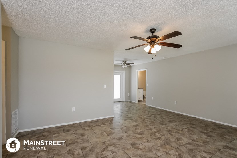 the spacious living room with ceiling fan and tile flooring
