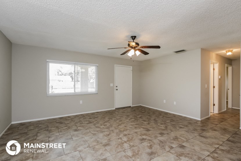 the spacious living room with ceiling fan and tile flooring