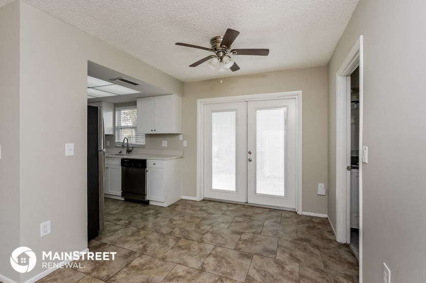 a living room with a ceiling fan and a kitchen
