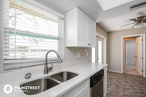 a kitchen with white cabinets and a sink and a window