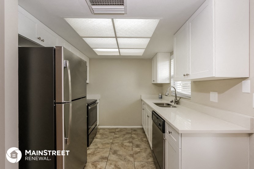 a kitchen with white cabinets and stainless steel appliances and a refrigerator