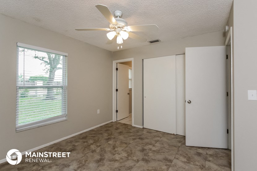 the living room of an apartment with a ceiling fan and a window